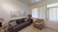 This single-floor residence at 12730 Monte Vista in Poway offers a well-organized layout designed for comfortable, functional living. The living area is generously proportioned, featuring vaulted ceilings that enhance the sense of openness and plush carpeting underfoot. Large windows fitted with vertical blinds allow natural light to fill the space while providing privacy, and a sliding glass door connects the living area to the outdoors.

The dining area sits adjacent to the living room, with a pass-through window opening directly into the kitchenette, creating a practical connection between the two spaces. The kitchenette is efficiently designed, featuring warm honey-toned wood cabinetry, granite countertops with a tile backsplash, a stainless steel refrigerator, microwave, and a single-basin sink—all finished with tile flooring.

The bedroom is a calm, carpeted retreat with ample natural light from a large window and sufficient space for standard furnishings. The bathroom features a wide granite-topped vanity with warm wood cabinetry, an open under-sink design for accessibility, and a large mirror that reflects light throughout the room. Overall, the unit presents a cohesive, neutral palette with consistent granite and wood finishes that lend a polished, unified character throughout.