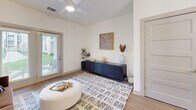 Located at 1155 Highway 62 in Charlestown, Indiana, this one-bedroom, one-bathroom residence offers a thoughtfully designed single-floor layout with modern finishes and a bright, cohesive aesthetic. The open-concept living and kitchen area serves as the heart of the home, where light-toned luxury vinyl plank flooring flows seamlessly throughout. The kitchen is outfitted with crisp white shaker cabinetry, quartz countertops, stainless steel appliances, and a central island with seating — all illuminated by a striking industrial-style pendant light fixture. The living room benefits from a ceiling fan and a glass door that welcomes natural light and outdoor views. The bedroom is a comfortable, carpeted retreat featuring a ceiling fan, a large window with outdoor views, and ample space for both rest and work. A dedicated closet provides convenient storage. The full bathroom features white cabinetry with a quartz vanity top, brushed nickel hardware, wood-look flooring, and a tub-shower combination. Throughout the residence, neutral wall tones and clean architectural lines create a calm, modern ambiance suited to everyday living.