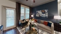 Located at 140 Grande Oaks Dr in Charleston, SC, this single-story residence offers a thoughtfully designed interior with modern finishes and a warm, contemporary aesthetic throughout. Wood-style flooring runs seamlessly across the living areas, anchoring each room with a cohesive, inviting feel.

The living room serves as a striking focal point, featuring a bold navy accent wall, large windows with floor-to-ceiling drapes, and direct access to an outdoor balcony, allowing abundant natural light and wooded views to fill the space. Ceiling fans are present throughout, adding both comfort and style.

The kitchen is well-appointed with light wood cabinetry, granite-style countertops, a full suite of stainless steel appliances including a range, microwave, dishwasher, and refrigerator, and a central island with bar seating — ideal for both cooking and casual dining.

The residence includes multiple bedrooms, each uniquely styled. One features a deep teal accent wall with decorative mirrors, while others offer neutral tones with plaid drapery and tree-lined window views. The bathrooms are finished with granite-topped vanities, wood-tone cabinetry, large mirrors, and wood-style flooring, maintaining the home's consistent design language. The overall ambiance balances modern sophistication with comfortable, livable charm.