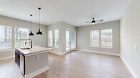 Located at 1100 Warburton Rd in Summerville, SC, this well-appointed single-story home offers a thoughtfully designed open-concept layout with three bedrooms, two bathrooms, and four closets. Light wood-look flooring flows consistently throughout the home, complemented by neutral gray walls and crisp white trim, creating a clean and cohesive aesthetic.

The kitchen and living area form the heart of the home, where a large central island with a white quartz countertop and a dual-basin sink serves as the focal point. Warm wood upper cabinetry pairs with dark lower cabinets, and stainless steel appliances complete the modern look. Stylish pendant lighting hangs above the island, while the adjoining living area benefits from multiple windows and a glass door that invite natural light and offer outdoor views.

The spacious primary bedroom provides a comfortable retreat, while additional bedrooms feature ceiling fans, natural light, and easy outdoor views through well-positioned windows. The primary bathroom is outfitted with a dual-sink dark vanity topped with stone counters, a large framed mirror, and contemporary matte black fixtures. A second full bathroom includes a tub-shower combination with tile surround and matching dark cabinetry. Generous closet space with wire shelving systems ensures ample storage throughout. Well-lit hallways connect each area of the home seamlessly.