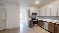 Located at 131 Village Parkway in Waxhachie, TX, this one-bedroom, one-bathroom unit offers a smart, efficiently designed single-floor layout. The combined kitchen and living area serves as the heart of the home, where the kitchen stands out with stainless steel appliances including a range, microwave, and dishwasher, complemented by gray shaker-style cabinetry, granite-look countertops, a tile backsplash, and light wood-style flooring that flows throughout the main areas. A hallway connects the living space to the private bedroom, which features warm neutral-toned walls, a ceiling fan with light fixture, and easy access to two closets for ample storage. The living area opens to a bright nook with large windows and a glass door, inviting in natural light and offering an outdoor view. The bathroom is clean and well-appointed with a full tub and shower combo featuring white tile surround, a granite-look vanity, and wood-style flooring. A dedicated laundry area adds everyday convenience to this well-rounded unit. Overall, the space presents a bright, modern aesthetic with thoughtful touches throughout.