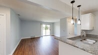 Located at 100 Lake Village Blvd in Auburn Hills, Michigan, this well-appointed one-bedroom, one-bathroom residence offers a thoughtfully designed single-level layout. Rich hardwood-style flooring flows throughout, lending warmth and continuity to every room.

The entrance welcomes you with a granite-topped half-wall that transitions into a bright dining area, illuminated by a stylish pendant light fixture and a natural-light-filled window. The open-concept layout connects the dining space seamlessly to the living room, which features a sliding glass door offering outdoor views and filling the space with natural light.

The kitchen is efficiently designed with white shaker cabinetry, granite countertops, stainless steel appliances, and a utility sink — providing both function and style. An adjacent pantry closet with built-in shelving adds valuable storage.

The generously sized primary bedroom features hardwood-style flooring, a walk-in closet outfitted with custom shelving and dual hanging rods, and a secondary closet for additional storage. The bathroom is finished with marble-patterned wall surround, a soaking tub, and warm-toned tile flooring with gold-accented fixtures. A dedicated laundry area and a hallway closet with additional shelving round out this practical and polished home.