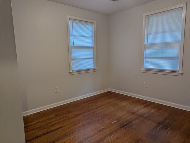 Sunlit bedroom with neutral paint, dual windows, and wood-style flooring. - 1527 Brookbank Ave