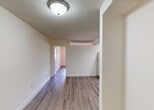 Located at 18335 NW 86 Ave in Hialeah, FL, this single-story unit offers a straightforward and functional layout designed for comfortable everyday living. Throughout the space, wood-look laminate flooring provides a warm, cohesive aesthetic, complemented by crisp white walls and textured ceilings.

The living area is open and well-proportioned, with a flush-mount ceiling light and direct sight lines to the kitchen and entry door, creating an easy flow between spaces. A large window in the main room allows natural light to filter in, with an in-wall air conditioning unit positioned beneath it for climate control.

The kitchen is efficiently arranged, featuring cream-toned cabinetry — both upper and lower — with a warm brown tile backsplash, a freestanding electric range, a full-size refrigerator, and a single-basin sink. Recessed lighting overhead ensures the workspace is well-lit.

The bedroom offers a clean, neutral environment with a louvered bifold closet door, providing practical storage. Additional rooms include a versatile secondary space accessible through the main hallway.

The bathroom is equipped with a full soaking tub and shower combination, enclosed by sliding glass doors with chrome hardware, and tiled surroundings featuring a decorative accent border. The overall design prioritizes clean lines and functional simplicity throughout.