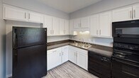 Located at 916 Lakecrest Ave in High Point, North Carolina, this two-story residence offers a clean, modern aesthetic throughout its interior spaces. The kitchen is well-appointed with white shaker-style cabinetry, dark granite-style countertops, light wood-look vinyl plank flooring, and black appliances including a refrigerator and dishwasher. A double-basin sink sits beneath under-cabinet lighting, and ample upper and lower cabinet storage provides practical functionality.

The living areas feature the same light-toned vinyl plank flooring, contributing to a cohesive and bright atmosphere. Neutral gray walls and textured ceilings are consistent throughout, creating a calm, versatile backdrop. The bedrooms are carpeted in warm neutral tones and feature windows with white blinds that allow natural light to filter in, lending each room an open, airy quality.

Additional rooms display similar flooring and neutral wall tones, with white trim and doors providing crisp contrast. The layout across both floors allows for clear separation between living and sleeping areas. Overall, the space presents a well-maintained, move-in-ready interior with consistent modern finishes and a straightforward, functional design.