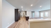 This single-floor unit offers a clean, modern aesthetic highlighted by light wood-look flooring that flows consistently throughout the space. The open-concept design connects the kitchen, dining, and living areas, creating a generous and well-connected communal zone. Recessed lighting and pendant fixtures illuminate the layout, complementing the neutral gray and beige tones found on the walls.

The kitchen is a functional centerpiece, featuring rich espresso-toned cabinetry with sleek bar-pull hardware, light granite countertops, an undermount sink, and a full suite of stainless steel appliances including a refrigerator, electric range, over-the-range microwave, and dishwasher. A peninsula with pendant lighting provides additional counter space and separates the kitchen from the open living area.

The spacious living area benefits from ample natural light through large windows dressed with horizontal blinds, and includes a ceiling fan. Bedrooms are well-sized, with walk-in closets featuring wire shelving systems. The bathroom includes a granite-topped vanity with dark cabinetry, a full soaking tub with shower, and matching flooring. A dedicated laundry area houses a full-sized Samsung washer and dryer.