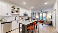 Located at 2370 Sever Rd in Lawrenceville, GA, this well-appointed two-bedroom, two-bathroom residence offers a thoughtfully designed single-floor layout. The open-concept living area seamlessly connects the kitchen, dining, and living spaces, creating an inviting, airy atmosphere. The modern kitchen is a standout feature, boasting crisp white shaker cabinetry, a classic subway tile backsplash, granite countertops, stainless steel appliances including a French door refrigerator, electric range, microwave, and dishwasher, plus an island with bar seating. The living room is bathed in natural light from floor-to-ceiling glass doors that open to a private balcony with outdoor views. The primary bedroom features a bold accent wall, plush carpeting, a ceiling fan, and generous natural light. Its en-suite bathroom includes a dual-sink granite vanity, walk-in glass shower with white tile surround, and wood-look flooring. The second bedroom is equally comfortable with its own closet access and a full bathroom featuring a soaking tub. Four closets, a dedicated laundry space, a utility room, and a hallway entry with a built-in coat rack add practical convenience throughout this well-finished residence.