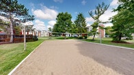 Located at 1820 Hickory Creek Ln in Columbus, Ohio, this outdoor recreational space features a full-sized sand volleyball court that serves as a standout community amenity. The court is laid out with well-maintained sand and equipped with a regulation net, providing an ideal setting for casual and competitive play alike. The expansive footprint offers ample room for players and spectators, making it a versatile gathering space for the surrounding community.

The court is framed by a well-kept lawn and mature trees, including tall evergreens and broad-canopied deciduous trees that provide natural shade and a pleasant, park-like atmosphere. The lush greenery surrounding the area creates a visually appealing and inviting environment. In the background, residential buildings constructed with classic brick and siding exteriors are visible, integrating the recreational space seamlessly within the broader community setting.

The open-air design allows for abundant natural light and unobstructed sky views, contributing to a bright and energetic outdoor ambiance. The combination of the sandy court surface, verdant surroundings, and residential backdrop makes this space a functional and aesthetically pleasing recreational destination for residents and visitors in Columbus, OH.