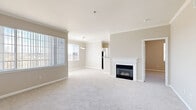 Located at 7550 S Blackhawk St in Englewood, Colorado, this well-appointed single-floor home offers two bedrooms and two bathrooms with a thoughtful, functional layout. The open living area is a welcoming centerpiece, featuring a classic white-mantled fireplace, soft carpet flooring, and natural light streaming through large windows with horizontal blinds. A pendant light fixture accents the adjacent dining area, creating a seamless flow for everyday living. The kitchen is equipped with stainless steel appliances — including a range, microwave, and refrigerator — complemented by white cabinetry, ample counter space, and wood-look flooring. Bright corner windows bathe the kitchen in natural light and offer pleasant outdoor views. The spacious primary bedroom includes a ceiling fan, carpeted flooring, and a walk-in closet outfitted with wire shelving for organized storage. The second bedroom is comparably comfortable, also featuring carpet and a window. A hallway connects the bedrooms and provides access to both bathrooms, one of which includes a soaking tub, tiled surround with decorative accent tiles, a single vanity, and wood-look flooring. Neutral warm-gray tones and white trim throughout lend the space a clean, cohesive aesthetic.