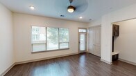 Located on Convergence Drive in Frisco, Texas, this two-story residence offers a thoughtfully designed layout spread across two levels. The main living area features rich dark hardwood flooring, large windows with horizontal blinds that invite abundant natural light, and a ceiling fan overhead. A transom-lit front entry door adds architectural character, while a built-in mudroom nook with dark cabinetry provides practical storage near the entrance.

The kitchen is well-appointed with dark espresso shaker-style cabinetry extending to the ceiling, a neutral tile backsplash, white quartz countertops, and a peninsula that serves as both a prep surface and casual dining space. Pendant lighting accents the peninsula, and stainless steel appliances—including a side-by-side refrigerator and dishwasher—complete the space.

Bathrooms feature light wood-look tile flooring, dark vanity cabinetry with white quartz surfaces, and tiled tub-shower combinations accented with mosaic tile borders. The primary bathroom includes a dual-sink vanity with a large framed mirror and brushed nickel fixtures.

Upstairs, carpeted bedrooms offer ceiling fans and generous natural light. A walk-in closet with multi-level shelving and hanging rods provides ample storage. Hallways connect bedrooms and bathrooms efficiently, making the upper level both functional and comfortable.