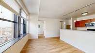 Located in the heart of downtown Indianapolis, this one-bedroom, one-bathroom residence offers a clean, modern aesthetic throughout. Light hardwood flooring runs continuously across the open-concept layout, lending warmth and visual cohesion to every room.

The combined kitchen and living area serves as the centerpiece of the space. The kitchen features rich wood cabinetry, granite countertops, a peninsula breakfast bar, and stainless steel appliances including a refrigerator and microwave. Pendant lighting over the peninsula adds a polished finishing touch. Track lighting extends into the living area, which flows seamlessly toward the hallway and bedroom.

Large, bold-framed windows in the living and bedroom areas fill the space with natural light and frame elevated views of the Indianapolis cityscape — a standout feature of the residence. The bedroom is comfortably sized, appointed with a ceiling fan and direct access to a dedicated walk-in closet outfitted with wire shelving on multiple walls for generous storage.

The bathroom maintains the same cohesive design language, with a wood vanity, granite countertop, and warm wall lighting. Crisp white walls and trim throughout create a bright, airy atmosphere that complements the natural light. Hallways connect all areas efficiently, contributing to a well-organized and functional floor plan.