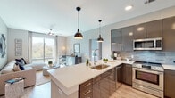 Located at 838 Morrison Dr in Charleston, SC, this contemporary single-floor residence showcases a thoughtfully designed open-concept layout with modern finishes throughout. The kitchen serves as a central highlight, featuring sleek dark cabinetry with a glossy finish, quartz countertops, a large center island with bar seating, stainless steel appliances including a French door refrigerator, electric range, and built-in microwave, all complemented by a subtle tile backsplash and stylish pendant lighting. Light hardwood-style flooring flows seamlessly throughout the space.

The living area is bright and airy, with large floor-to-ceiling windows that invite abundant natural light and offer views of the surrounding Charleston streetscape. Multiple bedrooms provide private retreats, each featuring ceiling fans, generous natural light, and French door access to private balconies with outdoor views. The primary bathroom offers a dual-sink vanity with dark cabinetry and quartz countertops, wood-look flooring, and direct access to a walk-in closet. A secondary bathroom features a navy blue vanity, a tub-shower combination, and a clean, modern aesthetic. The overall ambiance is polished and contemporary, balancing functionality with refined style.