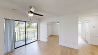 Located in Miami, FL, this single-floor, 2-bedroom, 2-bathroom residence offers a clean, modern aesthetic throughout. Light wood laminate flooring flows seamlessly across every room, complemented by crisp white walls and textured ceilings that lend a bright, airy feel.

The open-concept kitchen is a standout, featuring white shaker cabinetry, granite countertops extending across a spacious peninsula with an undermount sink, and a full suite of stainless steel appliances including a refrigerator, range, and built-in microwave. A skylight-style ceiling fixture adds warmth to the cooking area.

The living room opens directly to a private balcony through sliding glass doors, offering picturesque views of lush greenery and a tranquil water feature. A ceiling fan provides comfort year-round.

The generously sized primary bedroom includes its own sliding glass door access to an outdoor space, a walk-in closet with wire shelving, and a ceiling fan. The second bedroom features a ceiling fan, natural window light, and a louvered closet door. Both bathrooms are finished with granite-topped vanities, white cabinetry, and tiled tub-shower combinations with chrome fixtures.

A dedicated laundry area with full-size washer and dryer adds everyday convenience to this well-designed Miami home.