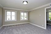 This single-floor space offers a practical and well-organized layout, as visible in the floor plan, encompassing a living area, kitchen, multiple bedrooms, and a bathroom. The living area is finished with plush grey carpeting, neutral taupe walls, and crown molding, creating a clean and cohesive aesthetic. A built-in shelving unit adds functional storage, while an open passage connects seamlessly to the kitchen.

The carpeted bedrooms continue the neutral color palette, with large windows that invite abundant natural light and views of surrounding greenery. One bedroom features a ceiling fan with integrated lighting, enhancing both comfort and airflow. White-trimmed doors and crisp baseboards throughout contribute to a tidy, consistent finish.

The kitchen is equipped with warm-toned wood cabinetry, light countertops, and stainless steel appliances including a range and over-the-range microwave. A built-in countertop ledge provides additional workspace or casual dining. Light tile flooring contrasts with the carpeted areas elsewhere in the unit.

The bathroom features a full tub and shower combination with white tile surround, a wall-mounted sink with classic fixtures, a mirrored medicine cabinet, and a window that brings in natural light.