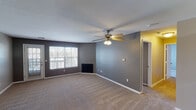 Located at 2133 W Wyndham Hill Dr NE in Grand Rapids, Michigan, this single-floor unit offers a practical and well-organized layout suited for comfortable everyday living. The living room serves as the central gathering space, finished with plush carpeting, neutral gray walls, and a textured ceiling. A ceiling fan with an integrated light fixture provides both airflow and ambient lighting, while a fireplace adds a focal point to the room. Large windows allow natural light to filter in, and a glass-paneled door provides direct access to an outdoor space, enhancing the connection to the exterior.

The kitchen is efficiently arranged with warm wood-toned cabinetry lining both walls, offering generous storage. It is equipped with a gas range, refrigerator, dishwasher, and microwave, alongside a double sink set into white countertops. Wood-look flooring runs throughout the kitchen, adding warmth and durability. A pass-through opening connects the kitchen to the adjacent living and dining areas.

The bedrooms are carpeted and feature neutral tones, with individual windows that bring in natural light. Two bathrooms serve the unit, each including a vanity with wood cabinetry, white countertops, and wood-look flooring. One bathroom features a shower-tub combination, while the other includes a standalone shower.