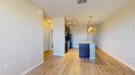 Located at 10207 Dwell Court in Orlando, FL, this one-bedroom, one-bathroom residence offers a well-designed single-floor layout that efficiently utilizes its compact footprint. The open-concept living and kitchen area serves as the heart of the home, featuring warm hardwood-style flooring, neutral-toned walls, and natural light streaming through a window with outdoor views. The kitchen is a standout highlight, equipped with rich dark wood cabinetry, stainless steel appliances including a refrigerator, range, and microwave, a tile backsplash, and a central island with granite countertops and an undermount sink. Pendant lighting and track lighting illuminate the space, adding a modern touch. A hallway connects the main living area to the private quarters, with a louvered closet for additional storage along the way. The bedroom is carpeted for comfort, features a ceiling fan, windows with blinds that offer outdoor views, and includes a dedicated closet. The bathroom is outfitted with a combined tub and shower enclosed by sliding glass doors, a granite-topped vanity, and tile flooring. Throughout the unit, clean lines and a neutral palette create a cohesive and functional living environment.