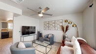 This two-story home offers a practical and inviting layout spread across two floors, with living areas on the ground level and bedrooms above. The living room features light-toned wood-style flooring, a ceiling fan with integrated lighting, and a clean, neutral color palette that creates an open and welcoming ambiance. A separate dining area provides an intimate space for meals, accented by bright white walls and wood-plank flooring. The kitchen is well-equipped with gray shaker-style cabinetry, granite-look countertops, black appliances including a range and refrigerator, and a window that brings in natural light. A hallway with white panel doors connects the main living areas with closets providing additional storage. Upstairs, the primary bedroom is generously proportioned, featuring large windows that invite natural light, wood-style flooring, and ample space for a sitting area. The second bedroom is bright and cheerfully designed, also with wood-style flooring and access to a hallway. The shared bathroom is finished with gray vanity cabinetry, a granite-look countertop, a framed mirror, tile flooring, and a shower-tub combination. Throughout, the home maintains a consistent, modern aesthetic with neutral tones and clean finishes.