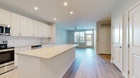 Located at 2020 W Morehead Street in Charlotte, NC, this single-floor residence offers a thoughtfully designed open-concept layout with modern finishes throughout. The kitchen is a standout feature, boasting white shaker-style cabinetry, a classic subway tile backsplash, quartz countertops, stainless steel appliances including a French door refrigerator, electric range, microwave, and dishwasher, and a large central island ideal for dining or meal prep. The kitchen flows seamlessly into the living area, which is bathed in natural light from sliding glass doors leading to a private balcony. Durable wood-look flooring runs throughout the main living areas, lending a warm and cohesive aesthetic. The bedrooms are generously sized, featuring plush carpet, large windows with views of surrounding greenery, and abundant natural light. The primary bathroom includes a sleek walk-in glass shower with white subway tile, while the secondary bathroom offers a full tub-shower combo with matching tile work. Both bathrooms feature light wood-toned vanities with quartz countertops and modern fixtures. A dedicated laundry area with a full-size washer and dryer and wire shelving adds everyday convenience. The overall ambiance is clean, contemporary, and bright.
