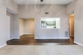This single-story unit in Macon, Georgia offers a well-organized layout with a cohesive neutral color palette and a mix of flooring materials that define each functional zone. The living area features vaulted ceilings and a ceiling fan, with plush carpeting underfoot and a sliding glass door that opens to a private patio, allowing natural light to fill the space and providing outdoor views.

A defining architectural feature is the pass-through window connecting the living and dining area to the kitchen, creating an open sightline between the two spaces. The galley-style kitchen is equipped with dark cabinetry, dark granite-style countertops, stainless steel appliances including a refrigerator and gas range, and light wood-style vinyl flooring, offering a functional and stylish cooking environment.

The bedrooms are carpeted and include ceiling light fixtures; one features vaulted ceilings while another receives natural light through a window with blinds. Additional rooms with dark hardwood-style vinyl flooring provide flexible use as a dining area or office. The bathroom includes a vanity with dark cabinetry and granite-style countertops, a tub-shower combination, and matching wood-style flooring, maintaining a consistent design aesthetic throughout the unit.