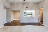 This single-story unit in Macon, Georgia offers a well-organized layout with a cohesive neutral color palette and a mix of flooring materials that define each functional zone. The living area features vaulted ceilings and a ceiling fan, with plush carpeting underfoot and a sliding glass door that opens to a private patio, allowing natural light to fill the space and providing outdoor views.

A defining architectural feature is the pass-through window connecting the living and dining area to the kitchen, creating an open sightline between the two spaces. The galley-style kitchen is equipped with dark cabinetry, dark granite-style countertops, stainless steel appliances including a refrigerator and gas range, and light wood-style vinyl flooring, offering a functional and stylish cooking environment.

The bedrooms are carpeted and include ceiling light fixtures; one features vaulted ceilings while another receives natural light through a window with blinds. Additional rooms with dark hardwood-style vinyl flooring provide flexible use as a dining area or office. The bathroom includes a vanity with dark cabinetry and granite-style countertops, a tub-shower combination, and matching wood-style flooring, maintaining a consistent design aesthetic throughout the unit.