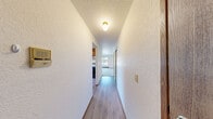 Located at 314 N 134th St in Seattle, WA, this two-bedroom unit offers a well-organized single-floor layout designed for comfortable everyday living. The open kitchen and living area serves as the heart of the unit, where warm honey-toned wood cabinetry, dark granite countertops, and wood-look vinyl flooring give the kitchen a clean, functional character. A dishwasher and refrigerator are included, and a window brings in natural light. The adjacent living room is generously proportioned, featuring soft carpeting, textured ceilings, and large sliding glass doors that open onto a private balcony — flooding the space with natural light and providing views of the surrounding greenery and neighborhood. The primary bedroom is a comfortable size, featuring plush carpet, a wide sliding-door closet, and a window overlooking lush tree canopy, creating a tranquil retreat. The second bedroom also features carpet flooring, a closet, and its own window with leafy outdoor views, making it equally well-suited as a guest room or home office. Baseboard heating is present throughout. The overall ambiance is light, neutral, and move-in ready, with a practical layout that maximizes the available footprint in a convenient North Seattle location.