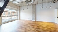 Located at 2200 Market St in Denver's vibrant Curtis Park neighborhood, Unit 101A is a single-floor loft-style residence that blends industrial character with modern finishes. The open-concept layout is anchored by warm hardwood flooring that flows throughout the space, creating a cohesive and inviting atmosphere.

The living area showcases striking industrial design details, including exposed ductwork, a concrete support column, and pendant lighting suspended from soaring ceilings. Large windows allow natural light to pour in, brightening the open floor plan and offering views of the surrounding neighborhood.

The kitchen is both functional and stylish, featuring warm-toned wood cabinetry, granite countertops with a subtle speckled pattern, and a full suite of stainless steel appliances including a refrigerator with ice maker, range, and microwave. A built-in wine rack adds a refined touch, while a peninsula with a sink provides additional prep space and casual seating potential. Slate tile backsplash ties the kitchen's aesthetic together beautifully.

The bathroom continues the space's design narrative with a dramatic floor-to-ceiling slate tile accent wall in rich earth tones, paired with hardwood-style flooring and clean white fixtures. The overall ambiance of this residence is one of urban sophistication, merging raw industrial elements with polished, contemporary details.