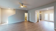 Located on W Eisenhower Pl in Fayetteville, Arkansas, this two-story residence offers a clean, modern aesthetic throughout. The main level features an open living area with durable wood-look flooring, neutral gray walls, and a ceiling fan, creating a bright and functional gathering space. A staircase leads to the upper level, while French doors with frosted glass panels provide access to the exterior, allowing natural light to filter in. The kitchen is well-equipped with white shaker-style cabinetry, granite-look countertops, a classic subway tile backsplash, stainless steel appliances including a range, microwave, and refrigerator, and a pantry for additional storage. The bathrooms are finished with tile flooring, granite-topped vanities, and full tub-shower combinations. The upper level hosts carpeted bedrooms, each fitted with ceiling fans. The primary bedroom includes a walk-in closet, while secondary bedrooms feature standard closets. A conveniently tucked half bath with a sloped ceiling, granite vanity, and tile floor is also present. Throughout the home, consistent neutral tones and quality finishes create a cohesive and comfortable living environment.