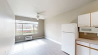 Located at 737 SW 17th Ave in Portland, Oregon, this one-bedroom, one-bathroom unit offers a practical and well-organized single-floor layout. The open-plan living, dining, and kitchen area forms the heart of the unit, bathed in natural light from large windows that frame urban views of the surrounding Portland cityscape. Light-toned luxury vinyl plank flooring runs throughout, complementing the neutral warm-beige wall palette. A ceiling fan with integrated lighting anchors the living space, while a wall-mounted HVAC unit ensures year-round comfort.

The kitchen is efficiently laid out in an L-shape configuration, featuring white cabinetry with warm wood-tone trim, laminate countertops, a stainless steel sink, and white appliances including a refrigerator, electric range, and microwave. A dedicated pantry provides additional storage. The bedroom is a comfortable, well-proportioned room with a window overlooking the neighborhood and a mirrored closet. A full bathroom rounds out the unit, complete with a tub/shower combination, a single vanity sink, and a large mirror. Clean finishes and a functional layout make this unit an efficient and comfortable urban residence.