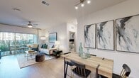 This contemporary single-floor residence offers a thoughtfully designed open-concept layout that seamlessly connects the main living areas. The kitchen is a standout feature, equipped with stainless steel appliances, rich dark wood cabinetry, white quartz countertops, a large center island with bar seating, and pendant lighting — ideal for both everyday cooking and entertaining. Light wood-style flooring flows through the kitchen and living areas, enhancing the bright, airy atmosphere created by white walls and recessed lighting.

The open dining area transitions naturally into the living room, which features vaulted ceilings, a ceiling fan, and large sliding glass doors that open onto a private balcony with outdoor views. The living room is generously proportioned, offering ample space for relaxed seating arrangements. Track lighting adds a modern touch overhead.

Two well-sized bedrooms provide comfortable retreats, each carpeted and filled with natural light from large windows with blinds and ceiling fans. The bathrooms are finished with elongated tile flooring, white vanities with quartz countertops, soaking tubs, and illuminated mirrors, delivering a clean and polished aesthetic throughout the residence.