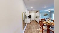 Located at 158 English Commons Dr in Lynchburg, VA, this single-floor, 2-bedroom, 2-bathroom residence offers a clean, modern design with thoughtful finishes throughout. The open-concept layout seamlessly connects the living room, dining area, and kitchen, all unified by warm wood-tone luxury vinyl plank flooring and neutral walls that invite natural light. The kitchen is well-equipped with white shaker cabinetry, granite countertops, stainless steel appliances, and a central island with bar seating — ideal for both everyday cooking and entertaining. The living room features a fireplace, ceiling fan, and sliding glass doors that lead to a private balcony with views of the surrounding community. Both bedrooms are carpeted for comfort and include ceiling fans and ample natural light from large windows. The primary bedroom offers generous proportions and walk-in closet space with built-in wire shelving. The bathrooms feature granite-topped vanities and wood-tone flooring consistent with the rest of the home. A dedicated laundry area and multiple closets provide practical storage solutions throughout. The property's exterior is situated within a well-maintained community with landscaped grounds and convenient parking access.