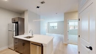 Located at 24 Jerome Ave in Bloomfield, CT, this two-bedroom, one-bathroom residence offers a thoughtfully designed single-floor layout with modern finishes throughout. The open-concept living and kitchen area serves as the heart of the home, featuring light wood-look flooring that flows seamlessly throughout the main living spaces. The kitchen is appointed with sleek wood-grain cabinetry, crisp white quartz countertops, stainless steel appliances including a refrigerator, electric range, built-in microwave, and dishwasher, as well as a peninsula with an undermount sink — ideal for casual dining or meal prep. The adjacent living room is bright and airy, benefiting from large windows that invite natural light and offer neighborhood views. The primary bedroom provides a comfortable retreat with plush carpeting, a generous closet with sliding doors, and a window overlooking the surroundings. The second bedroom also features light hardwood-style flooring and a window with exterior views. The full bathroom includes a soaking tub and shower combination with clean white tile surround, a wood-grain vanity, and white countertops. Two hallways connect the rooms efficiently, completing this well-organized and contemporary residence.