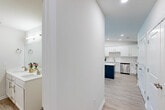 Located at 270 Lancer Drive in Nicholasville, Kentucky, this 2-bedroom, 2-bathroom single-floor home offers a thoughtfully designed layout with modern finishes throughout. The bright, open-concept living room features light wood-look flooring, a ceiling fan, and a large window that fills the space with natural light while offering pleasant outdoor views. A glass door provides direct access to a private balcony, extending the living area outdoors. The kitchen is a standout feature, boasting crisp white shaker cabinets, white quartz countertops, a full suite of stainless steel appliances, and a striking navy blue center island — a bold contrast that anchors the space. Recessed lighting illuminates the kitchen, adding to its clean, contemporary feel. Both bedrooms are carpeted for comfort and include windows with outdoor views and convenient closet access. The two bathrooms are finished with white vanities, modern fixtures, and wood-look tile flooring. A dedicated laundry room houses a full-size washer and dryer. Clean white walls, consistent flooring, and neutral tones create a cohesive and inviting atmosphere throughout this well-designed home.