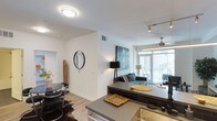 This thoughtfully designed single-floor residence showcases a clean, contemporary aesthetic throughout. The open-concept layout seamlessly connects the kitchen, dining, and living areas, creating a cohesive and functional living space. The kitchen is outfitted with stainless steel appliances, a gas range, a French door refrigerator, dark subway tile backsplash, rich wood cabinetry, and generous countertop space — ideal for both everyday cooking and entertaining. Light wood flooring runs throughout the main living areas, complementing the neutral palette.

The living room is bright and welcoming, anchored by large sliding glass doors that open to a private balcony, flooding the space with natural light and providing outdoor access. A ceiling fan adds both style and comfort to the room.

The bedroom continues the light-filled theme with its own sliding glass door leading to an outdoor area, offering a peaceful retreat. A spacious walk-in closet with built-in shelving and hanging rods provides ample storage.

The bathroom is finished with hexagonal slate-toned floor tiles, a warm wood vanity with open shelving, a wide mirror, and a full soaking tub with shower. Every detail reflects a modern, curated sensibility that balances style with everyday practicality.