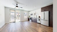 Located at 701 W Rio Salado Pkwy in Tempe, Arizona, this modern single-floor unit offers a thoughtfully designed open-concept layout that seamlessly connects the living area and kitchen. Rich hardwood-style flooring runs throughout, lending warmth and continuity to the space. The living area is bright and airy, featuring a sleek ceiling fan with a built-in light fixture and recessed lighting overhead. French doors open directly to a private balcony, allowing natural light to flood the interior while providing outdoor views of the surrounding Tempe landscape, including mature palm trees. The kitchen is a standout feature, showcasing a two-tone cabinet design with crisp white upper cabinetry and deep espresso-toned lower cabinets, complemented by white subway tile backsplash and light quartz countertops. Stainless steel appliances — including a range, microwave, dishwasher, and French door refrigerator — complete the contemporary culinary space. Black hardware and fixtures add a refined, modern accent throughout. The bathroom is clean and well-appointed, featuring a tiled tub-and-shower combination with white vertical subway tile, dark gray floor tile, and matte black hardware. The bedroom provides a generous, open feel with continued hardwood-style flooring and a ceiling fan, creating a comfortable and functional retreat.