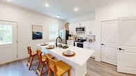 Located at 5612 Harbor Walk Way in Knoxville, Tennessee, this two-floor home offers a clean, modern aesthetic defined by crisp white walls, wood-look flooring, recessed lighting, and crown molding throughout. A welcoming entryway hallway leads into the main living areas, setting a bright and airy tone from the moment you enter.

The open-concept kitchen is a standout feature, showcasing white shaker cabinetry, stainless steel appliances—including a refrigerator, range, and built-in microwave—and a generously sized island with a built-in sink and seating for multiple guests. The kitchen connects naturally to the living room, which features a ceiling fan, recessed lighting, and windows that invite natural light into the space.

The bedrooms are well-proportioned and comfortable, each outfitted with ceiling fans and windows providing natural light. One bedroom includes a reading nook area framed by teal drapes.

The bathrooms maintain the home's modern style, with one featuring a glass-enclosed shower with subway tile, matte black fixtures, and hardwood-style flooring. A powder bath offers a sleek pedestal sink with a frameless mirror. A dedicated laundry area with a full-size washer and dryer adds everyday convenience.