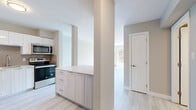 Located at 109 Greenpark Close in Halifax, Nova Scotia, this junior one-bedroom, one-bathroom unit offers a thoughtfully designed single-floor layout with a clean, contemporary aesthetic throughout. Light wood-style flooring runs continuously across the entire space, complementing the soft neutral tones of the walls and creating a bright, cohesive feel.

The open kitchen and living area serves as the heart of the unit. The kitchen is well-appointed with stainless steel appliances — including a refrigerator, electric range, built-in microwave, and dishwasher — paired with two-tone cabinetry featuring light wood lower cabinets and crisp white uppers. A subtle tile backsplash adds texture, while the light countertops provide ample workspace. A structural column with a built-in cabinet peninsula defines the transition between the kitchen and living area.

The living room is airy and filled with natural light from a sliding glass door that opens to a private balcony overlooking a lush green outdoor area. The bedroom is a comfortable size, featuring a large closet with sliding doors, a window with garden views, and baseboard heating. The bathroom is clean and functional, offering a full soaker tub and shower combination with white tile surround. Two hallways provide practical flow and access throughout the unit.