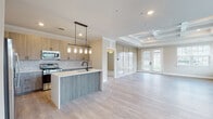 This single-floor residence showcases a thoughtfully designed open-concept layout that seamlessly connects the kitchen and living areas. The kitchen is a standout feature, equipped with stainless steel appliances including a gas range, microwave, and French door refrigerator. Light wood cabinetry pairs with a herringbone-patterned tile backsplash, while a two-tone island with a white quartz countertop and gray wood-look base provides additional prep space and seating. Pendant lights with glass shades hang above the island, adding a refined touch.

The living area features light hardwood-style flooring and a coffered tray ceiling that adds architectural depth. French doors allow natural light to fill the space and provide outdoor access. A separate carpeted room with its own tray ceiling and pendant light fixture offers flexibility as a bedroom or flex space.

The bathroom is finished with large-format tile flooring, a tub-shower combination accented by a mosaic tile inlay, a wood-tone vanity with white countertop, and matte black hardware throughout. A dedicated laundry room includes upper cabinetry, a utility sink, and hardwood-style flooring. The attached garage features an automatic opener and concrete flooring, completing this well-appointed home.