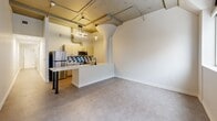 Located on Prospect Avenue in Cleveland, OH, this one-bedroom, one-bathroom unit offers a thoughtfully designed layout across a single floor. The open-concept living, dining, and kitchen area serves as the heart of the space, showcasing striking industrial character with exposed concrete ceilings, visible ductwork, and structural columns that lend a loft-inspired aesthetic. The kitchen is well-appointed with stainless steel appliances, light wood cabinetry, a geometric tile backsplash, and a peninsula countertop with bar-height seating — ideal for both cooking and casual dining. Pendant lighting adds a modern touch overhead. The living area features durable concrete-style flooring and is illuminated by natural light from a window with a street view. The carpeted bedroom offers a comfortable retreat with a wall-mounted mini-split HVAC unit and a double sliding-door closet providing ample storage. A second closet is available in the hallway for additional storage needs. The bathroom is clean and contemporary, featuring white hexagonal tile flooring, a glass-enclosed walk-in shower with matte black fixtures, and a wood-toned vanity. A utility room and dedicated entrance complete the functional floor plan of this urban residence.