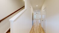 Located at 7437 Russellville Road in Bowling Green, Kentucky, this two-story home offers a thoughtfully designed layout spread across two floors. Light hardwood-style flooring flows consistently throughout the home, creating a bright and cohesive aesthetic.

The main floor features an open-concept living and kitchen area, where warm-toned cabinetry, a peninsula with a built-in sink, white appliances, and an elegant chandelier combine to create an inviting, functional space. Natural light enters generously through exterior-facing windows and a glass door, enhancing the airy feel. A hallway and staircase connect the main level to the upper floor, with recessed lighting and a clean white finish throughout.

Upstairs, the layout includes two well-sized bedrooms, each with light flooring, ceiling fixtures, and windows that bring in natural light. The spacious primary bedroom includes a ceiling fan and dedicated closet space. A dedicated laundry room on the upper floor adds everyday convenience, complete with washer and dryer hookups and overhead shelving.

Three bathrooms are distributed across the home, featuring clean, bright finishes with gold-accented hardware and a tub-shower combination. Two closets and multiple hallways ensure ample storage and easy circulation throughout. The home presents a clean, move-in-ready appearance with a consistent neutral palette.