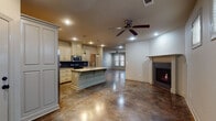 Located at 3 Farrah Ln in Little Rock, Arkansas, this two-story home offers a thoughtfully designed layout with a mix of flooring materials and finishes that create a distinctive interior character. The main level is anchored by a striking open-concept kitchen and living area, unified by richly stained, polished concrete floors that lend a contemporary yet warm aesthetic. The kitchen is well-appointed with cream cabinetry, a bold navy tile backsplash, stainless steel appliances, granite countertops, and a central island with a contrasting teal base and pendant lighting overhead. Ceiling fans keep the spacious living area comfortable, while a brick-surround fireplace adds a cozy focal point. A half bath on this level features a teal vanity with quartz countertop and a large mirror. The laundry room includes upper cabinetry and dedicated hookups. Upstairs, bedrooms feature plush carpet, ceiling fans, and natural light from windows. A primary bathroom includes a vessel sink vanity with granite countertops and access to a well-organized walk-in closet with double hanging rods and built-in shelving. An additional bedroom with light wood-style flooring and attic access rounds out the upper level, offering versatile space for various needs.