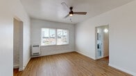 Located at 260 S Mariposa Ave, this single-floor unit blends classic architectural character with modern updates. The main living area is defined by warm hardwood flooring that extends throughout the space, whitewashed exposed brick accent walls, and a ceiling fan that adds both function and charm. Windows fitted with blinds invite generous natural light while offering views of the surrounding neighborhood. A wall-mounted heater provides efficient climate control.

The open layout flows between the living area and additional rooms via clean, bright doorways. The kitchen is well-appointed with gray shaker-style cabinetry, crisp white quartz countertops, a subway tile backsplash, and a stainless steel gas range with a hood vent—delivering a polished, functional cooking space.

The bathroom features floor-to-ceiling dark marble-style tile surrounding a soaking tub and shower combination, complemented by a white vanity with a mirrored medicine cabinet and a frosted window that allows natural light while maintaining privacy.

Overall, the space presents a cohesive aesthetic that balances original character elements—like the exposed brick—with contemporary finishes, creating a clean, inviting atmosphere throughout.