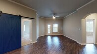 This single-story residence offers a thoughtfully designed layout with a variety of functional and attractive features throughout. The main living area is characterized by rich, dark hardwood-style flooring, crown molding, and a ceiling fan, with natural light streaming in through a glass door that opens to an outdoor balcony or patio. A striking blue sliding barn door serves as a standout architectural detail, adding a modern-rustic touch to the space.

The kitchen is efficiently arranged with light maple cabinetry, granite countertops, a dark subway tile backsplash, and stainless steel appliances including a refrigerator, electric range, and built-in microwave. Conveniently adjacent to the kitchen is an in-unit laundry closet housing a full-size washer and dryer.

The bedrooms feature plush carpeting and an abundance of natural light from multiple windows with outdoor views. One bedroom includes a walk-in closet, while vaulted ceilings in certain rooms enhance the sense of spaciousness.

Both bathrooms are finished with granite-topped white vanities, backlit round mirrors, and tile flooring. The primary bath features a dual-sink vanity, while the secondary bath includes a walk-in shower with sliding glass doors.