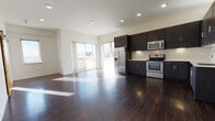 Located at 820 N Sherman St in Denver's vibrant Capitol Hill neighborhood, this modern single-floor unit offers a thoughtfully designed open-concept layout with a clean, contemporary aesthetic throughout. Rich dark hardwood flooring extends across the living and kitchen areas, creating a cohesive and sophisticated foundation for the space.

The kitchen is well-appointed with dark espresso cabinetry extending to the ceiling for ample storage, white subway tile backsplash, light countertops, and a full suite of stainless steel appliances including a refrigerator with ice maker, electric range, built-in microwave, and dishwasher. The kitchen flows seamlessly into a spacious living area bathed in natural light from large sliding glass doors that open to a private balcony offering urban Denver views.

A standout rustic barn door provides a charming design contrast against the otherwise modern interior, offering flexible room division. The bedrooms feature the same dark hardwood flooring and crisp white walls, providing versatile spaces filled with natural light.

The bathrooms are finished with tile flooring and include a primary bath with a frameless glass walk-in shower, a navy blue vanity with white countertop and large mirror, and a second full bath with a soaking tub and tiled surround. Recessed lighting throughout completes the polished, modern feel of this Denver residence.
