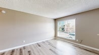Located at 1104 Palm Avenue in National City, CA, this one-bedroom, one-bathroom unit offers a practical and well-appointed single-floor layout. Throughout the main living areas, light-toned wood-style flooring creates a clean, cohesive look, while neutral warm beige walls and textured ceilings lend a consistent, understated aesthetic.

The open living, dining, and kitchen area forms the heart of the unit. The galley-style kitchen is efficiently designed with white cabinetry lining both sides, light countertops, a stainless steel sink, and white appliances including a range and refrigerator. Adjacent to the kitchen, the living and dining space benefits from a large window fitted with horizontal blinds, allowing natural light to brighten the room.

The bedroom is a comfortable size, finished with plush carpeting and its own window that brings in additional natural light and outdoor views. A dedicated closet provides practical storage. The unit also includes a full bathroom, completing its functional layout.

Overall, the space presents a clean, move-in-ready feel with a neutral palette throughout, making it easy to personalize. Its compact yet efficient design makes thoughtful use of every area, offering a straightforward and comfortable living environment in the National City community.