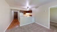 Located at 241 Ottawa Bend Dr in Morris, Illinois, this one-bedroom, one-bathroom unit offers a thoughtfully organized layout across a single floor. The open-concept living and kitchen area forms the heart of the space, where warm hardwood-style flooring transitions into plush carpeting in the living zone. The kitchen features a peninsula counter with white cabinetry, dark wood upper cabinets, a built-in electric range, a refrigerator, and a sink — all accented by under-cabinet lighting. A ceiling fan overhead provides both comfort and ambient light to the combined living area.

The bedroom is a comfortably sized retreat finished with soft carpeting and neutral walls. Natural light filters in through a window with views of surrounding greenery, while a set of louvered bi-fold closet doors provides ample storage. The room's clean, understated design allows for flexible furnishing arrangements.

The bathroom is highlighted by a walk-in shower enclosure clad in large-format marble-look tile with subtle grey veining, lending an elevated, clean aesthetic. Chrome fixtures complete the refined look.

A hallway connects the main living spaces to the bedroom and bathroom, offering a natural flow throughout the unit. The overall palette of warm neutrals and light tones creates a calm, welcoming atmosphere throughout.