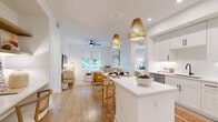Located at 5426 W Bay Center Dr in Tampa, FL, this single-floor, 2-bedroom, 3-bathroom residence offers a thoughtfully planned layout with a clean, modern coastal design. The open-concept kitchen and living area serves as the heart of the home, featuring white shaker cabinetry with matte black hardware, white quartz countertops, stainless steel appliances, and a central island with seating. Woven pendant lights add warmth overhead, while light wood-tone flooring runs throughout, enhancing the bright, airy atmosphere.

The living area flows naturally from the kitchen, benefiting from natural light and a ceiling fan. Both bedrooms are comfortably scaled, with the primary bedroom offering dedicated closet space outfitted with a built-in shelving and drawer system for organized storage. Bedroom windows frame views of surrounding palm trees, reinforcing the Florida coastal character of the space.

The bathrooms are finished in a crisp, contemporary style, featuring white tile surrounds, soaking tubs, extended vanities with illuminated mirrors, and matte black fixtures. Two hallways and a dedicated entrance provide a clear sense of circulation throughout. Overall, the residence presents a cohesive, well-lit interior with practical storage and refined finishes throughout.