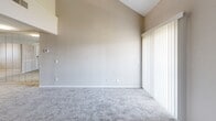 This two-story apartment at 2614 S Topeka St in Wichita, KS offers a well-designed layout spread across two floors. The main level features a combined kitchen and living area, where the living room stands out with soaring vaulted ceilings, plush carpeting, and a full wall of mirrored panels that enhance the sense of space and light. A sliding glass door with vertical blinds allows natural light to fill the room. The kitchen is equipped with warm oak cabinetry, ample counter space, a double sink, and white appliances including a range and dishwasher, all set on easy-care tile flooring.

Two carpeted bedrooms provide comfortable retreats. The primary bedroom on the upper level features angled ceilings with high windows that let in natural light, along with a built-in closet with louvered doors. The second bedroom on the main level includes a mirrored sliding closet and a window with an outdoor view. Both rooms are finished with neutral tones and textured ceilings. A hallway connects the main-level rooms, and a staircase leads to the upper floor. The full bathroom features a tub-shower combination with built-in wall shelving. Throughout the unit, neutral carpeting and warm beige walls create a clean, cohesive aesthetic.