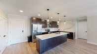 This single-floor residence showcases a thoughtfully designed layout with contemporary finishes throughout. The kitchen serves as a striking centerpiece, featuring dark espresso cabinetry that extends to the ceiling, a dramatic veined marble-style backsplash, and a generous island with a crisp white quartz countertop and an undermount sink. Three glass pendant lights hang above the island, while recessed lighting illuminates the stainless steel appliance suite. Light hardwood-style flooring runs throughout the main living and kitchen areas, adding warmth to the modern aesthetic.

The bedrooms are carpeted and neutrally toned, each equipped with ceiling fans for comfort. One bedroom offers city views through a well-positioned window, while others provide quiet, versatile spaces. A spacious walk-in closet with built-in shelving and dual hanging rods serves the primary suite.

Two bathrooms reflect consistent design quality. The primary bathroom features a dual-sink vanity with dark cabinetry, a white quartz countertop, a glass-enclosed shower, and hardwood-style flooring. The secondary bathroom mirrors this refined aesthetic, offering a tiled soaking tub with matte black fixtures, a single-sink vanity, and direct access to a walk-in closet.