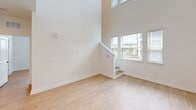 Located at 5151 Patriarch Place in North Augusta, SC, this two-story, one-bedroom, two-bathroom home offers a well-designed layout spread across two floors. The main level is generously sized, featuring a dramatic two-story open living area with soaring ceilings and large windows that flood the space with natural light. Light-toned luxury vinyl plank flooring runs throughout, complementing the clean, modern aesthetic defined by crisp white walls and trim.

The kitchen is a standout feature, boasting white shaker-style cabinetry, a classic subway tile backsplash, quartz countertops, a peninsula with pendant lighting, and stainless steel appliances including a dishwasher, range, and microwave. A door off the main living area provides outdoor access and additional natural light.

Two full bathrooms serve the home. One bathroom features a tub-shower combination with large-format tile surround and white vanity cabinetry with matte black hardware. The second bathroom offers a glass-enclosed walk-in shower with matching tile, built-in shelving, and a window for natural ventilation.

The upper level houses the private bedroom, a hallway, a closet, and a staircase, offering a quiet retreat from the main living areas. The bedroom is bright and functional, with a well-proportioned window. Throughout, the home maintains a cohesive, contemporary design with matte black fixtures accenting each space.