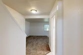 Located in Ovid, NY, this two-story home offers a functional and well-organized layout spread evenly across two floors. The main level features a carpeted living room bathed in natural light from front-facing windows, with a tiled entryway that transitions seamlessly into the living space. The kitchen is equipped with white cabinetry, dark laminate countertops, a stainless steel sink positioned beneath a large window, and a dishwasher. A dedicated laundry area with utility hookups and overhead cabinetry adds everyday convenience. Two bathrooms serve the home, one of which includes a full tub-shower combo with built-in shelving. A staircase leads to the upper level, where both bedrooms are located. The primary bedroom is generously sized and features multiple windows that invite natural light and views of surrounding greenery. The second bedroom is equally bright, with carpeted flooring and a large window. Throughout the home, textured ceilings, clean white walls, and neutral carpet create a simple and cohesive aesthetic. Five closets distributed across both floors provide ample storage, making this home as practical as it is comfortable.